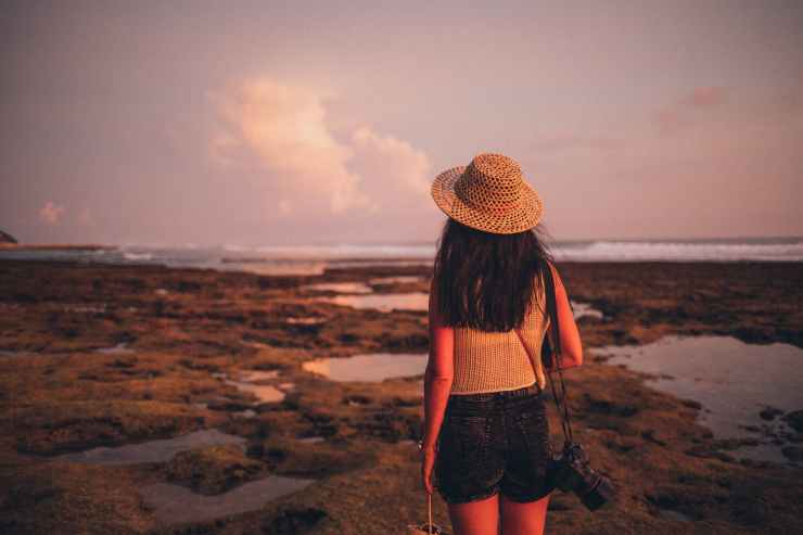 selective focus photography of woman standing on seashore facing body of water